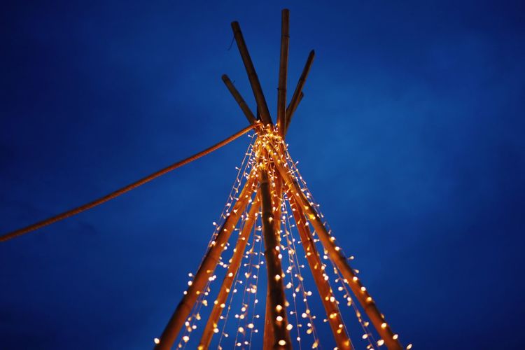 Low angle view of illuminated christmas lights against clear blue sky