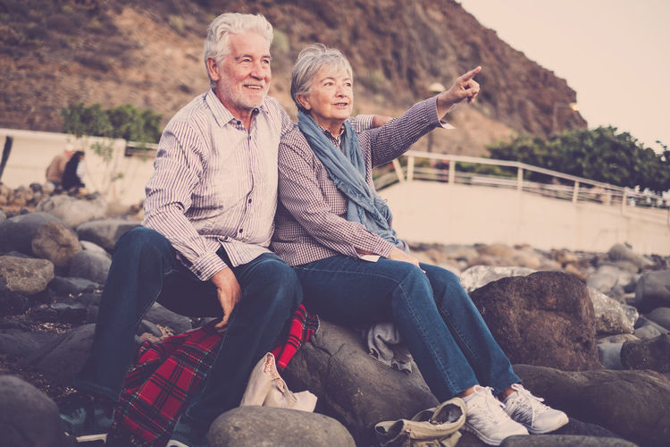 Senior couple sitting on rocks during sunset
