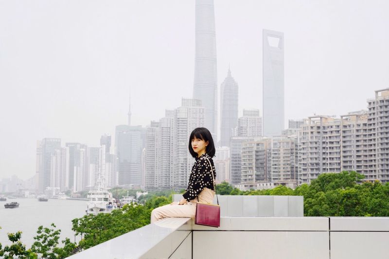 FULL LENGTH OF WOMAN AGAINST MODERN BUILDINGS IN CITY