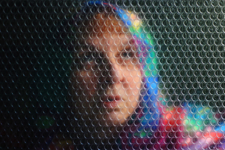 Portrait of woman with a colorful scarf on her head behind transparent wrapping bubbles