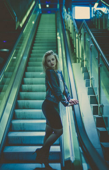 Low angle view of young woman standing on escalator