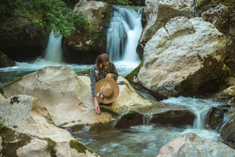 Young woman with hat enjoying natural water spring and slops