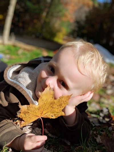 Close-up portrait of cute boy holding leaf