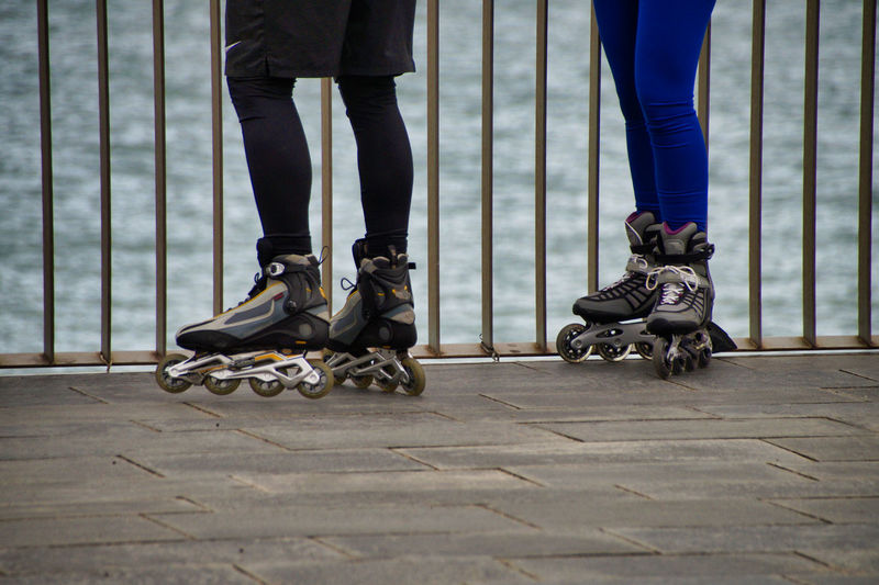 Low section of friends inline skating on promenade