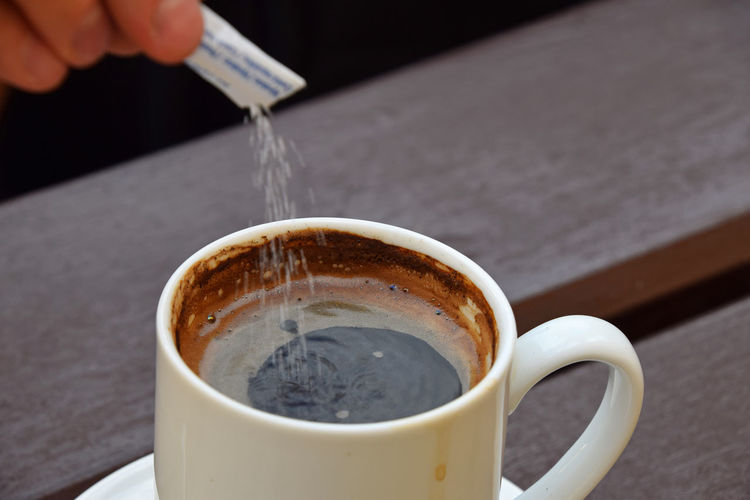 Cropped hand of person pouring sugar in turkish coffee