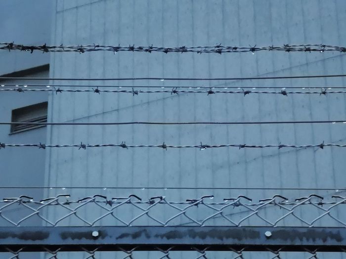Low angle view of barbed wire fence against building