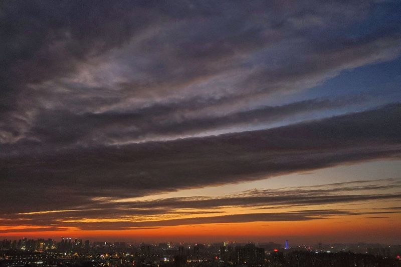 Scenic view of illuminated city against sky at sunset
