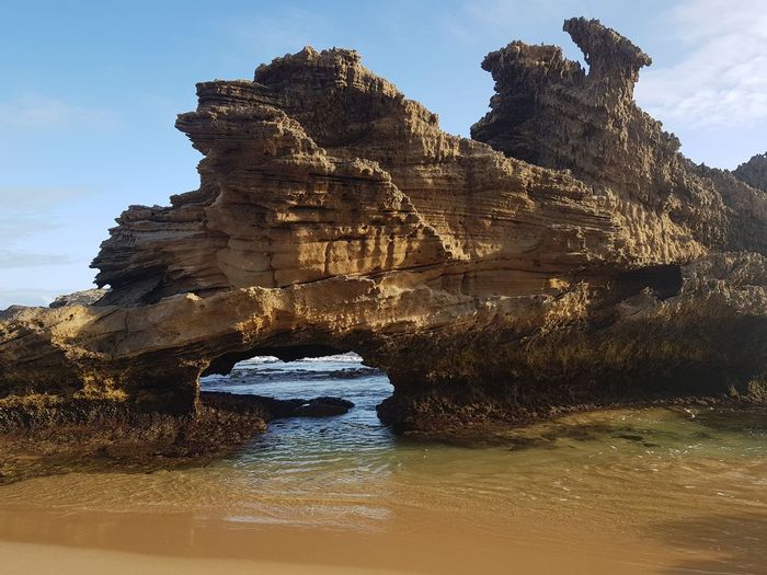 Rock formation in water against sky