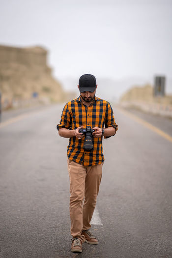 Thoughtful man holding camera, photographer walks outdoor with his camera