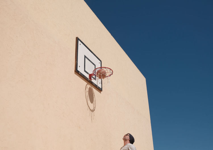 View of man under basketball hoop against clear sky