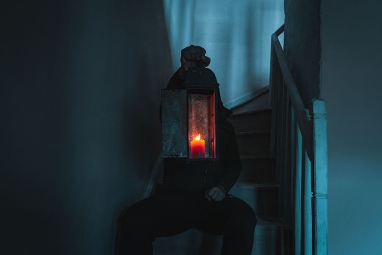 Man holding illuminated light on wall