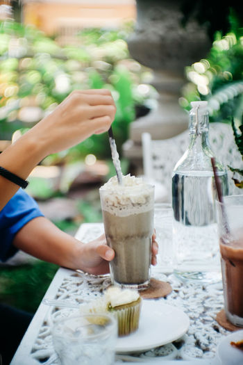 Cropped image of hand holding drink with ice cream