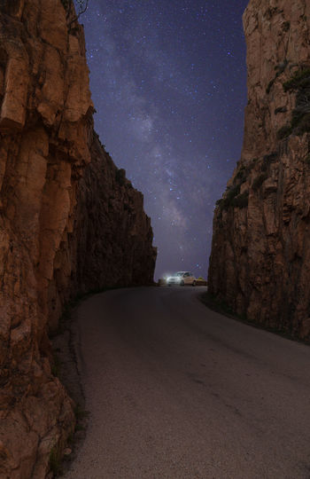 Road amidst rocks against sky at night