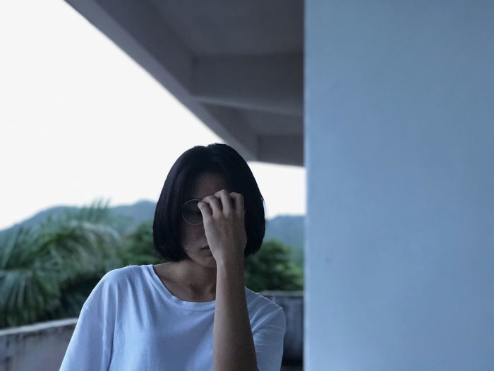 Young woman covering face at balcony
