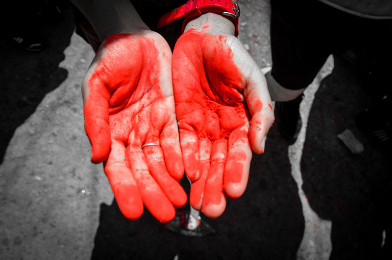 Low section of woman hand covered with red powder paint