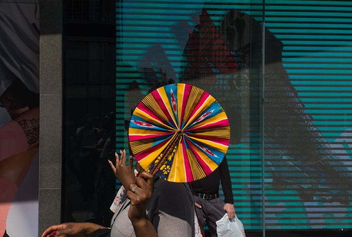 LOW SECTION OF PEOPLE HOLDING MULTI COLORED UMBRELLAS