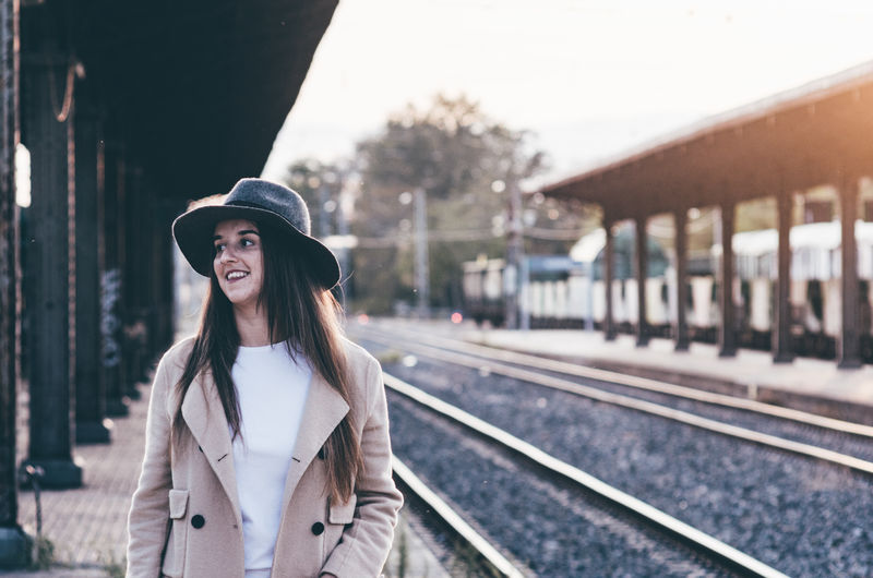 Portrait of smiling young woman standing on railroad station platform