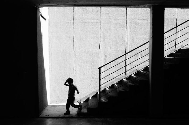 Silhouette side view of young kid walking on concrete staircase