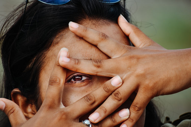 Close-up of woman covering face outdoors