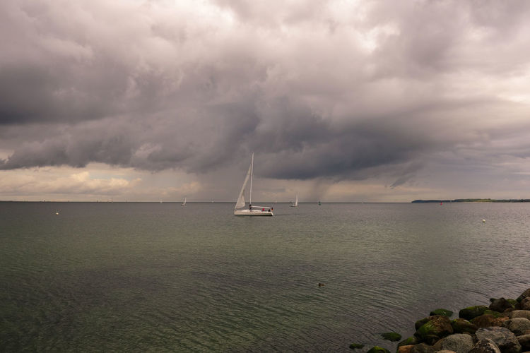 Sailboat in sea against storm clouds