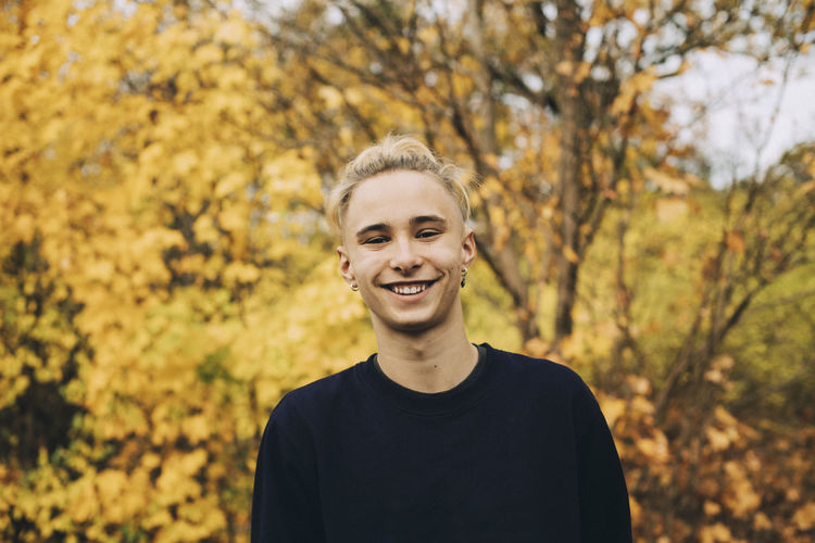 Portrait of smiling man standing against trees during autumn