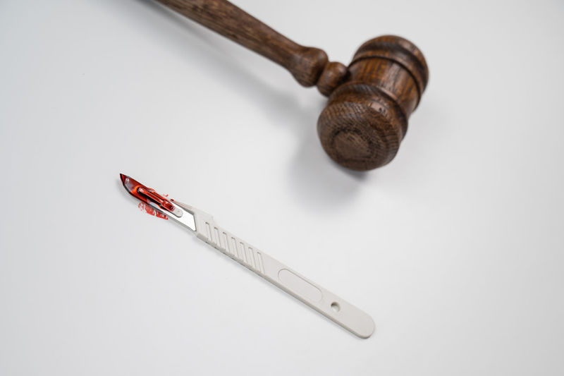 A scalpel covered in blood and a judge's wooden gavel