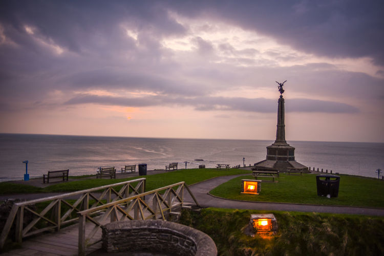 High angle view of war memorial by sea against cloudy sky