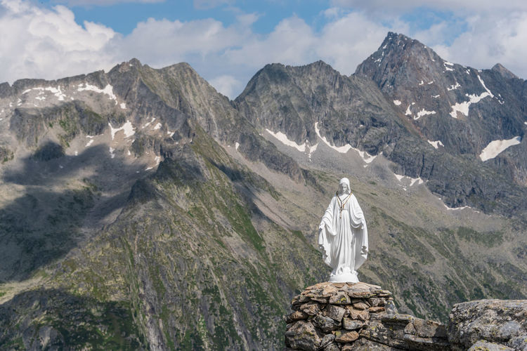 White statue of virgin mary, mother of god, placed on top of the mountain in background
