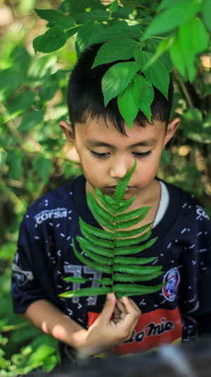 Cute thoughtful boy against plants