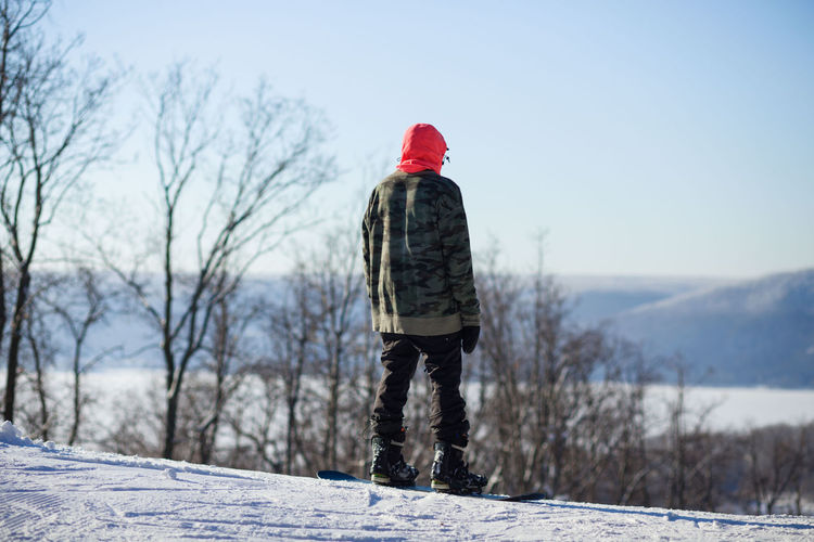 Man snowboarding on land against sky