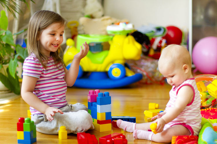 Siblings playing with toys on floor