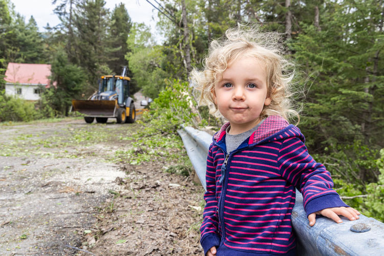 Portrait of young woman standing against trees