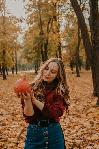 Portrait of smiling young woman holding autumn leaves