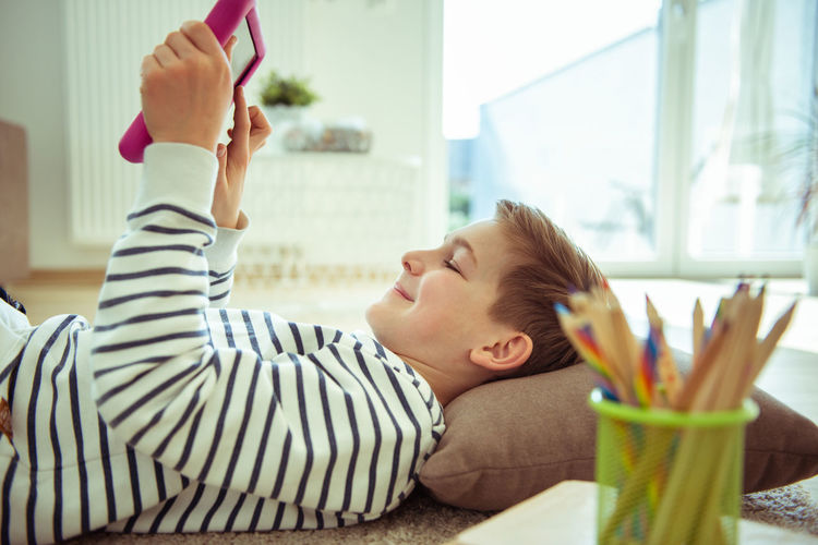 Boy using digital tablet while lying at home