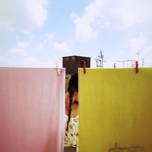 Woman standing by railing against cloudy sky