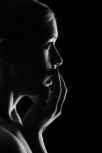 Side view of scared woman against black background