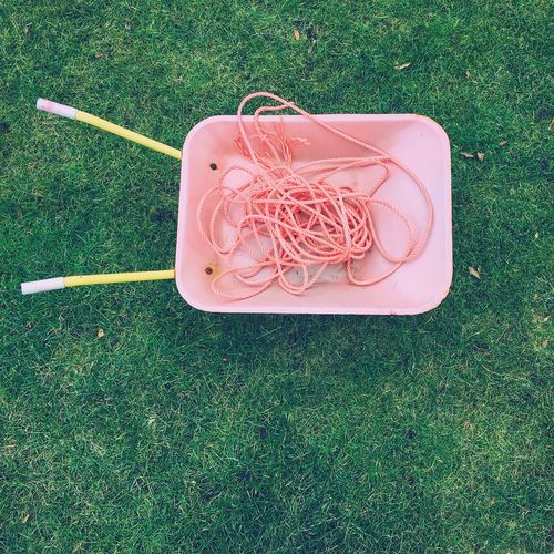 Directly above shot of ropes in wheelbarrow on grassy field