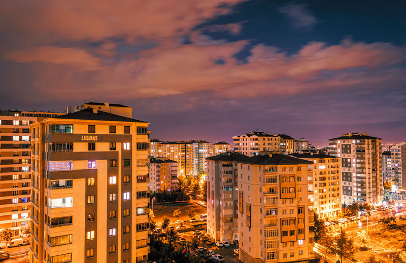 Illuminated buildings against sky at sunset