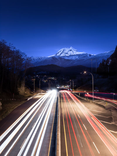 Light trails on road in city against sky at night