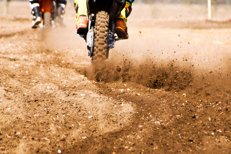 Low section of people riding motorcycle on dirt road