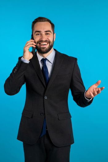 Full length of man using phone against blue background