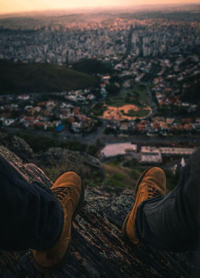 Low section of person on wood against cityscape and sky