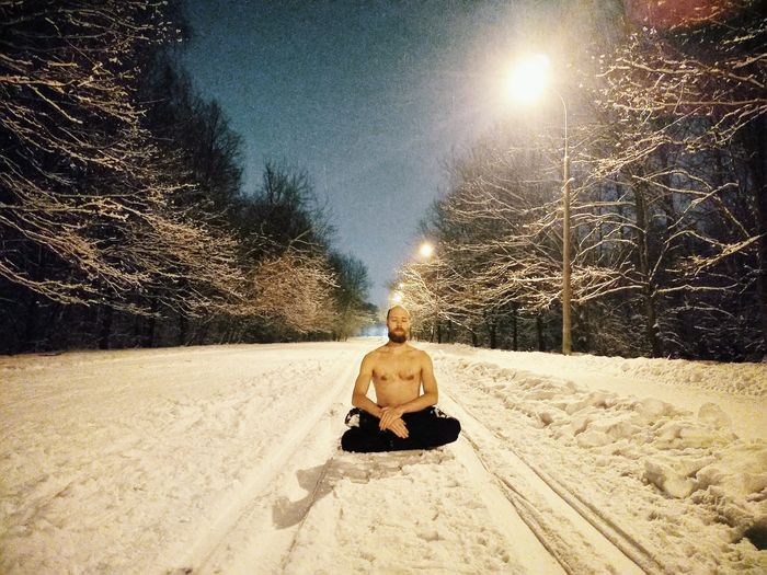 Rear view of man sitting on snow covered road