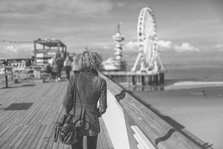 Rear view of woman standing on de pier against sky