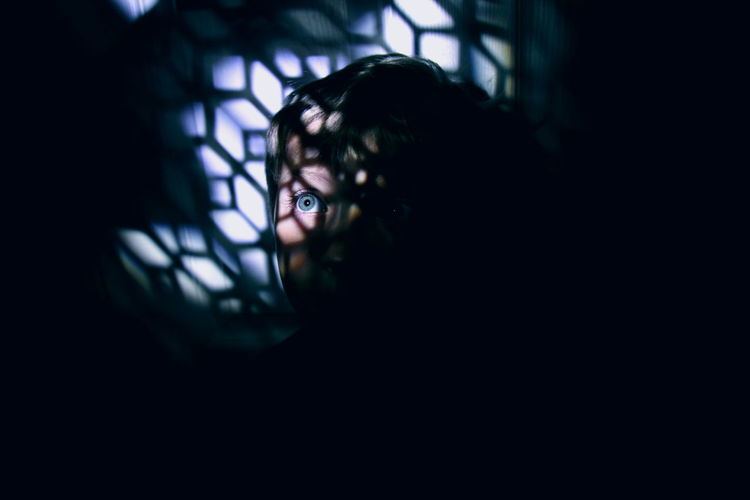 View of boy hiding in dark room