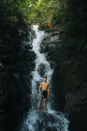 Man surfing on rock by river