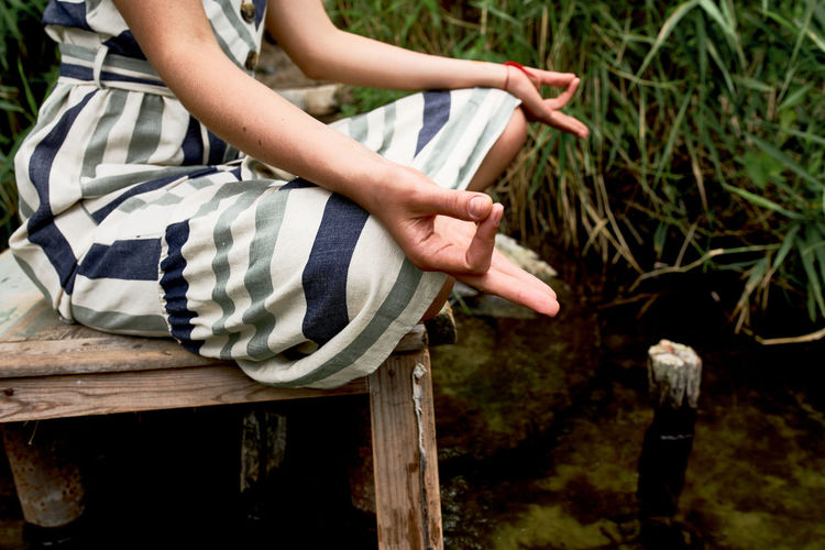 Closeup of young woman meditating and practicing yoga on the nature. 