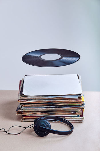Digital composite image of records with headphones on table against gray background