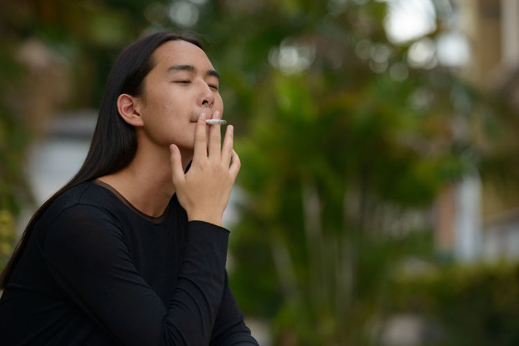 Young woman smoking cigarette outdoors
