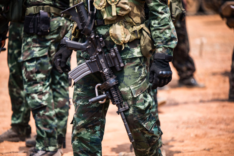 Midsection of army soldiers with rifle
